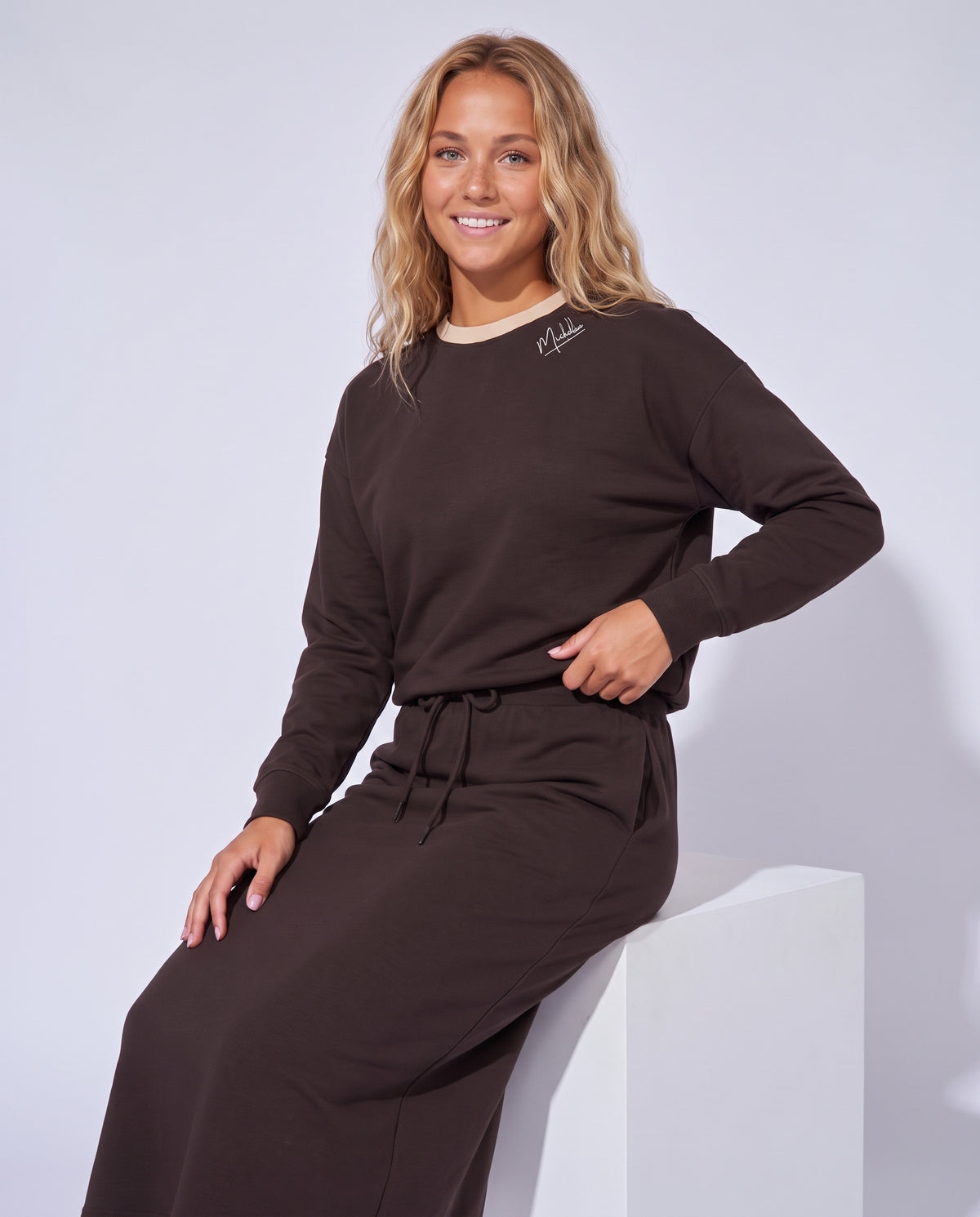 Chocolate-brown crewneck sweatshirt, small chest logo, long sleeves with ribbed cuffs