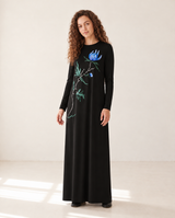 Model wearing a black long-sleeve nursing nightgown with a blue floral print and floor-length skirt.