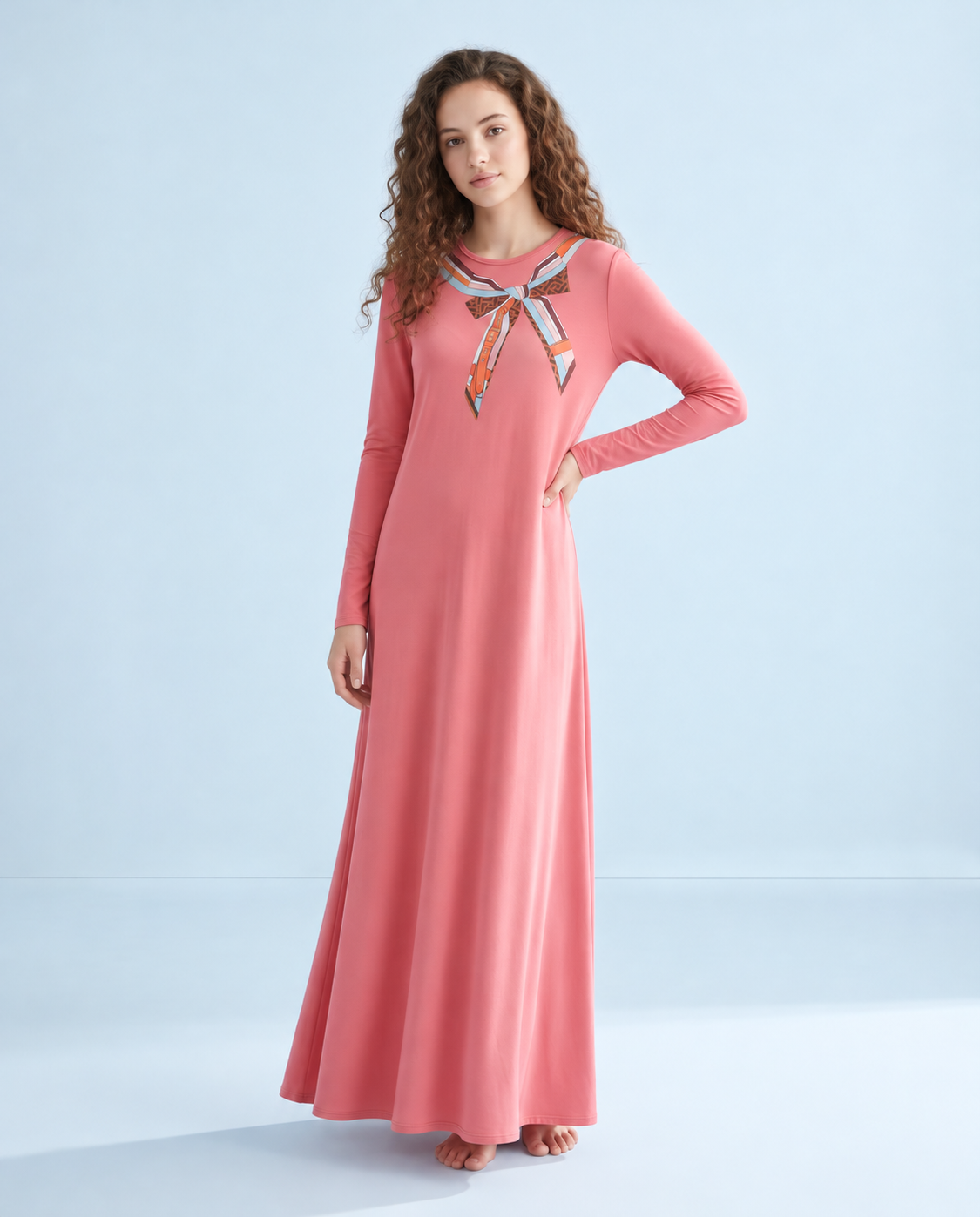 Model wearing a pink floor-length nightgown with long sleeves and scarf-print neckline