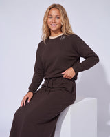 Chocolate-brown crewneck sweatshirt, small chest logo, long sleeves with ribbed cuffs