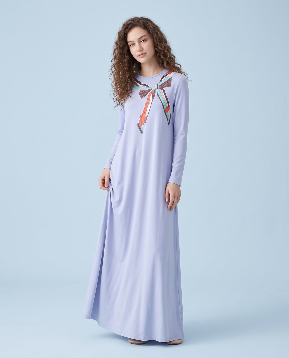 Model wearing a soft blue floor-length nightgown with long sleeves and a colorful scarf-print neckline