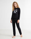 Black two-piece pajama set worn with a white bow print top and matching drawstring pants.