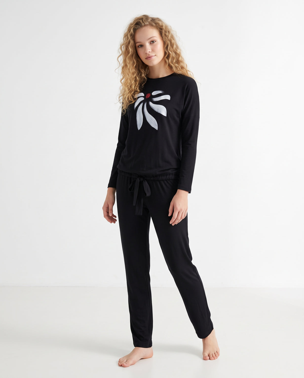 Black two-piece pajama set worn with a white bow print top and matching drawstring pants.