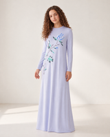 Model wearing a floor-length blue nightgown with long sleeves and floral branch print